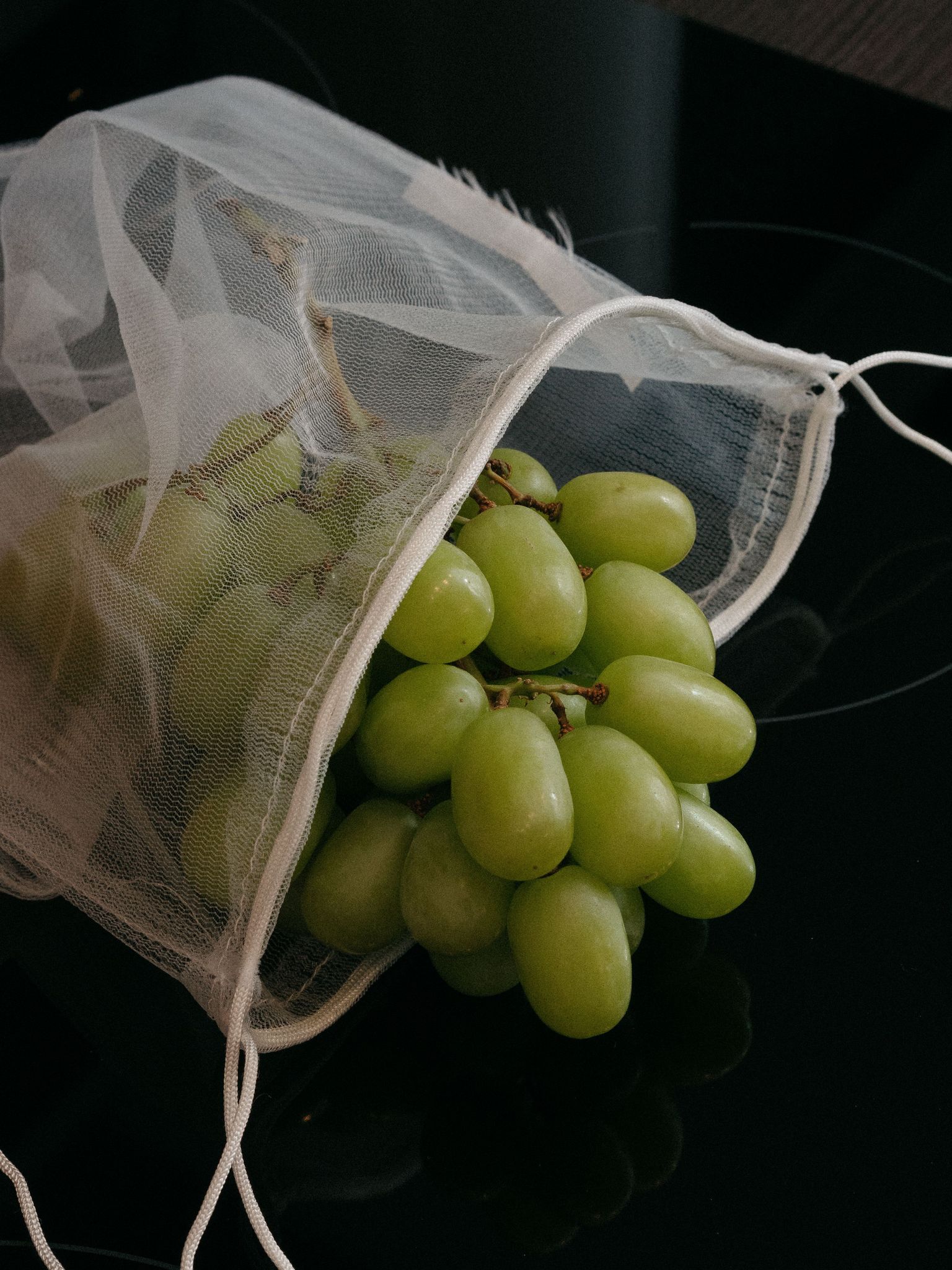 Grüne Trauben in durchsichtigem Netzbeutel.