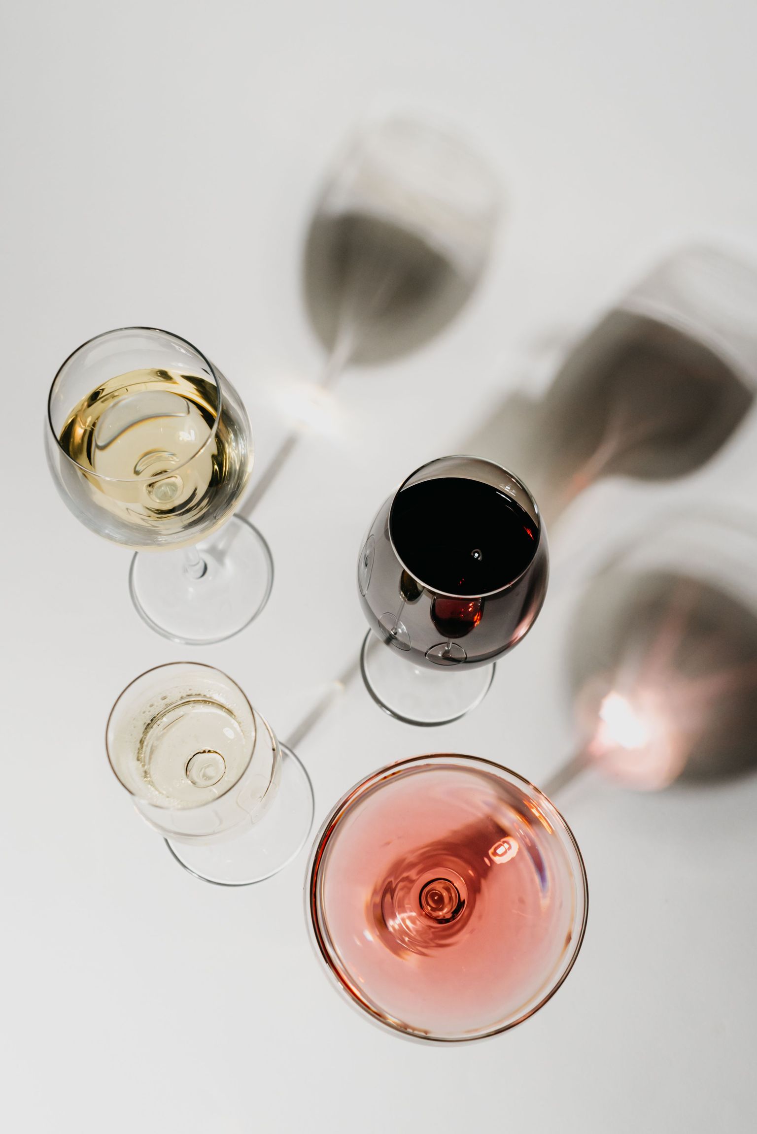 Vier Weingläser mit verschiedenen Weinsorten, von oben fotografiert.